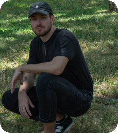 Black T-shirt dude crunching, wearing a black baseball cap: The Art Director at Once Advertisements, Krisztian Mezei, sitting on ‘Gellért-Hill’ in Hungary.